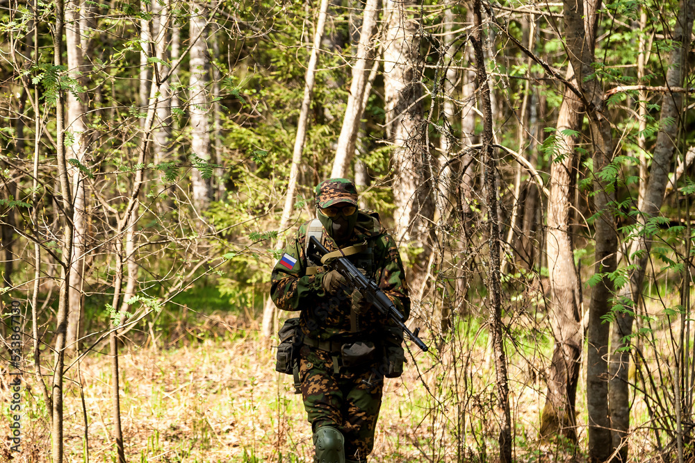 Russian soldier man dressed military camouflage uniform holding weapon in forest at nature background. Male border guard in country border holding machine gun on war. Copy text space