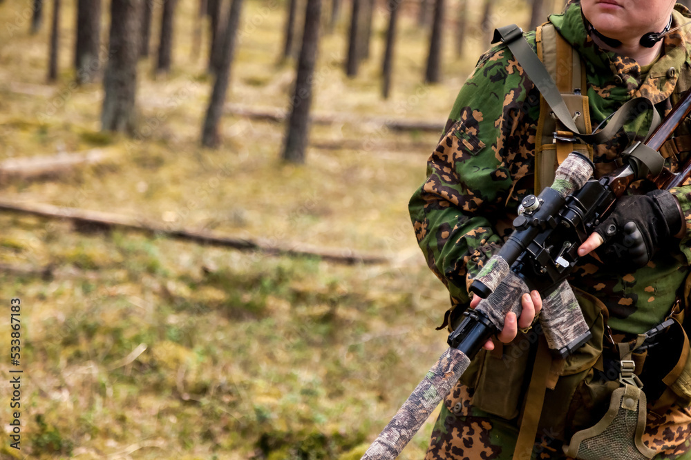 Close up rifle russian soldier man dressed military camouflage uniform holds weapon in forest at woodland background. Male border guard in country border holding machine weapon on war. Copy space