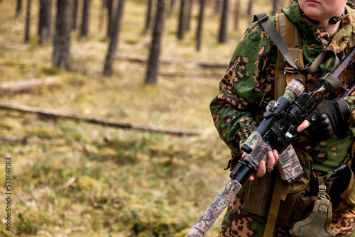 Close up rifle russian soldier man dressed military camouflage uniform holds weapon in forest at woodland background. Male border guard in country border holding machine weapon on war. Copy space