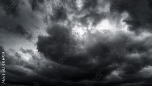 dark dramatic sky with black stormy clouds before rain or snow as abstract background, extreme weather, the sun shines through the clouds, high contrast photo