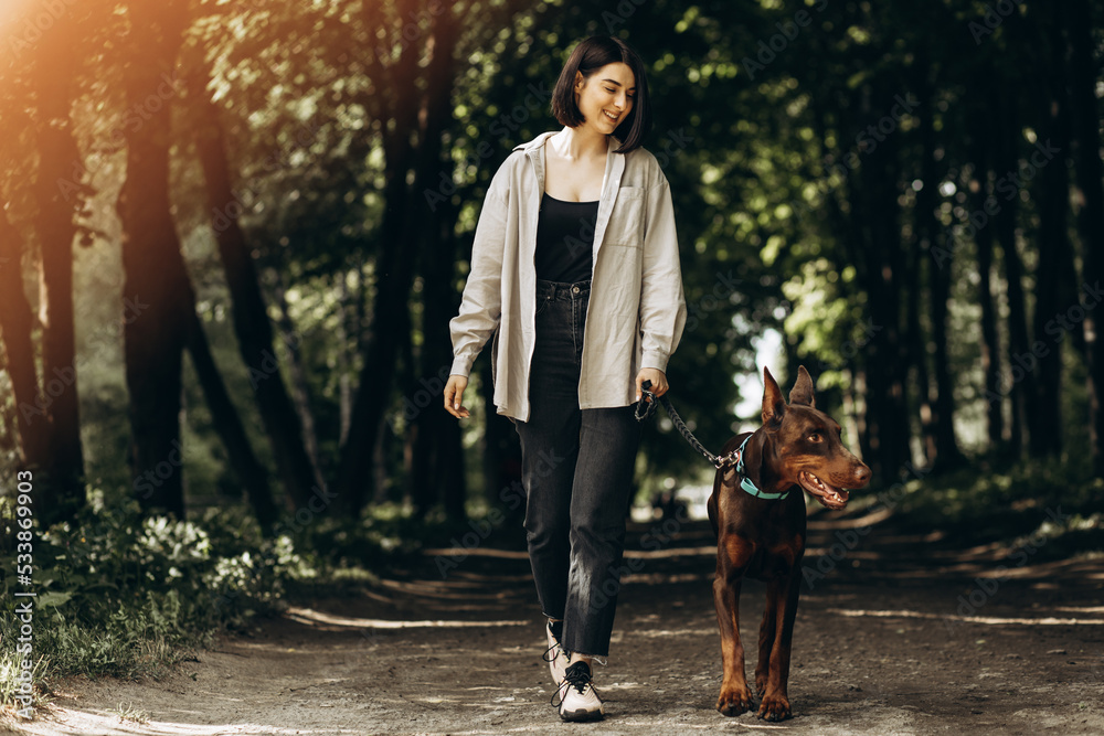Fototapeta premium Woman with her dog doberman having fun in park