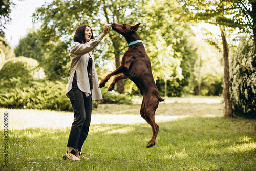 Woman with her dog doberman having fun in park © Petro