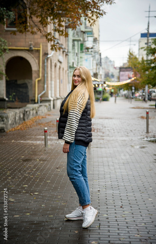 smiling woman with long blond hair in jeans walking on the street © Tetatet