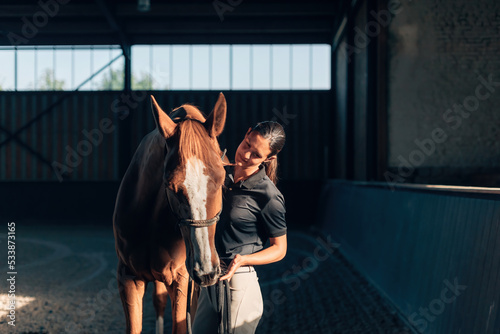 horsewoman riding instructor bonding with horse in horse farm