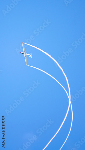 An acro glider in the sky with contrails