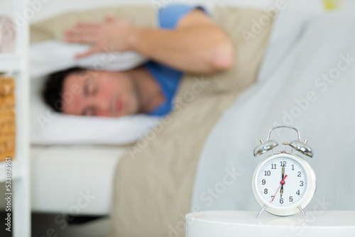man with alarm clock in bedroom photo