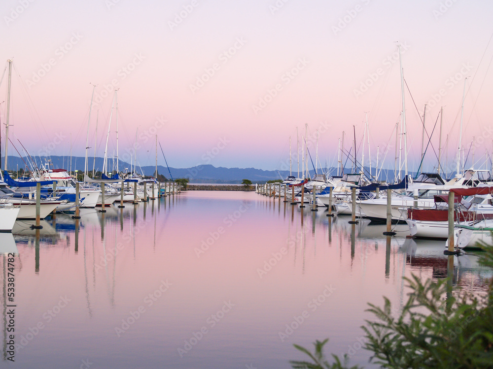 Boats moored in marina at sunset