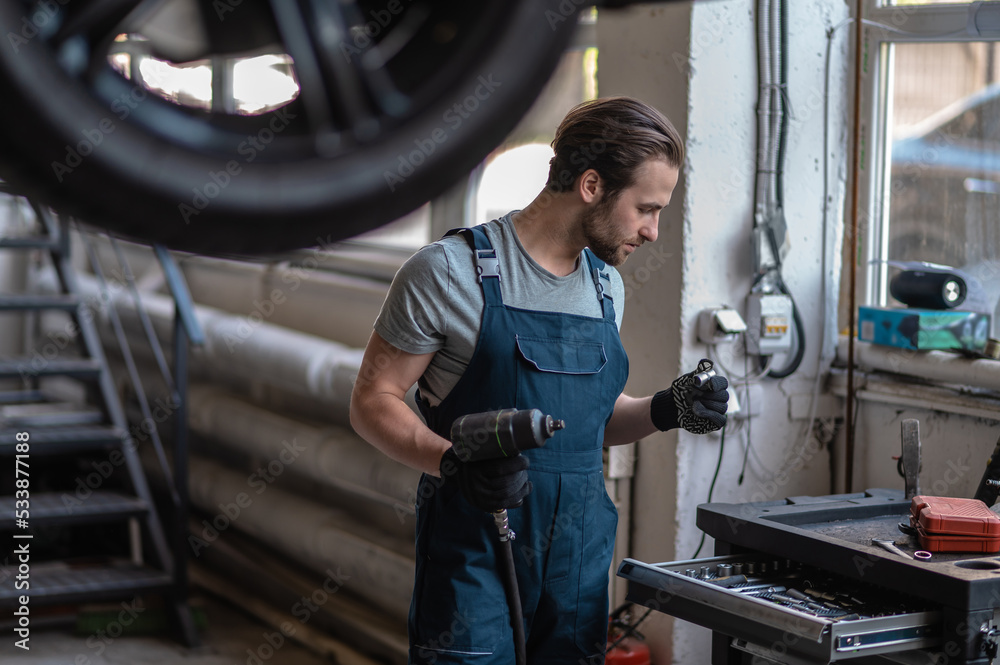 Automotive technician preparing for work in his workshop Automotive technician preparing for work in his workshop