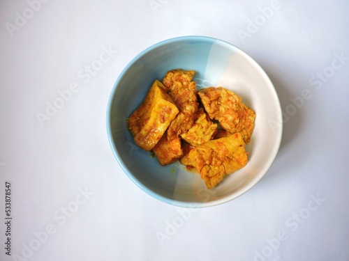 Fried tofu and tempeh in a bowl with white background