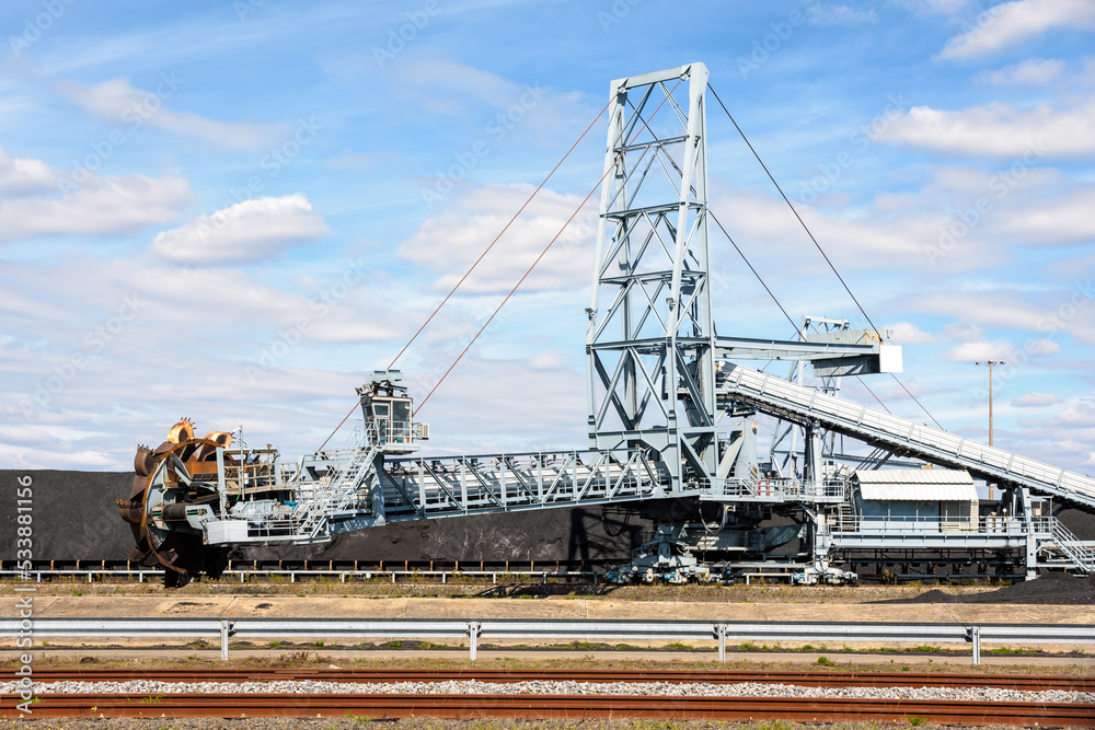 A bucket-wheel stacker-reclaimer and a coal stockpile in a thermal power station on a sunny summer day.