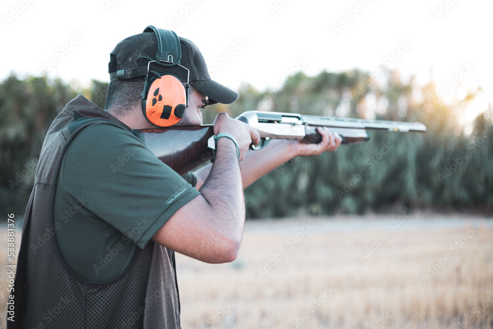 A young hunter shooting with a shotgun while wearing headphones. A young hunter shooting with a shotgun while wearing headphones.