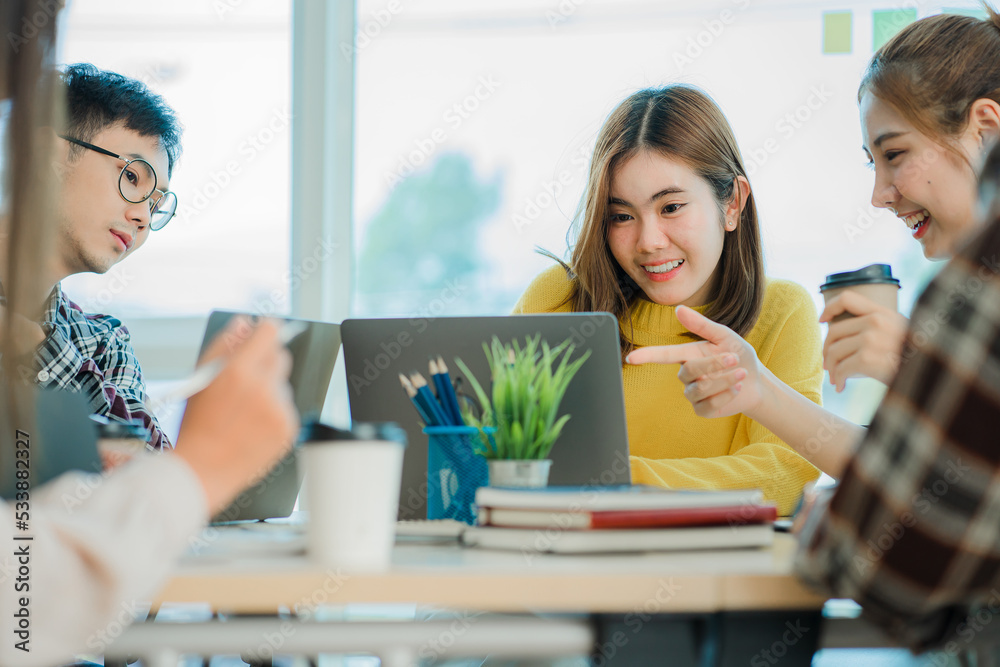 Obraz premium Asian creative teams sit and work together to share inspirational creativity in a workshop. Young modern businessmen are meeting with graph paper and laptop in the workplace.