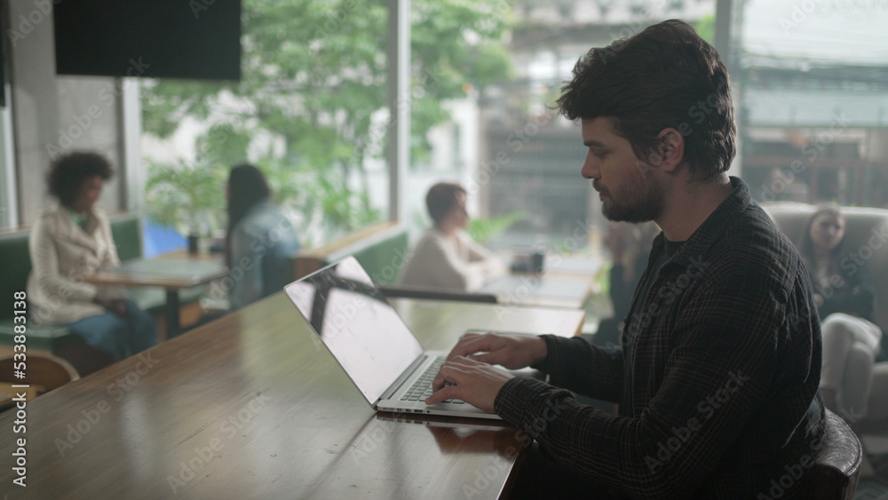 Entrepreneur in front of laptop at coffee shop. Young man freelancer using computer at cafe place Entrepreneur in front of laptop at coffee shop. Young man freelancer using computer at cafe place
