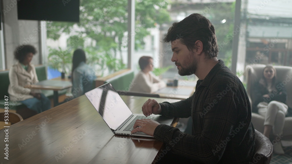 Entrepreneur in front of laptop at coffee shop. Young man freelancer using computer at cafe place Entrepreneur in front of laptop at coffee shop. Young man freelancer using computer at cafe place