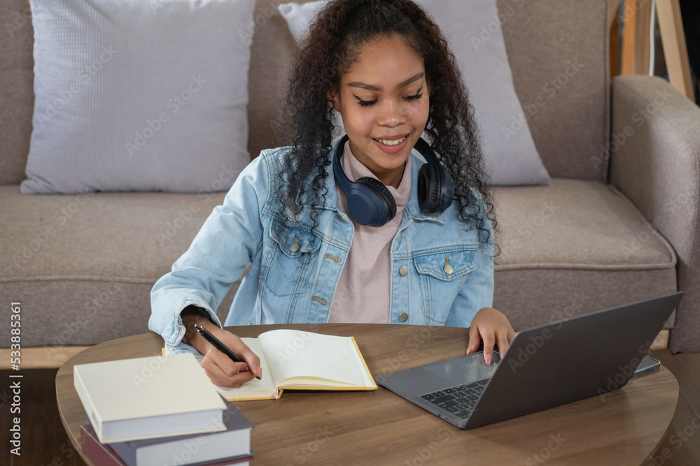 African woman, American, using laptop computer and wearing headphones for online learning. African woman, American, using laptop computer and wearing headphones for online learning.