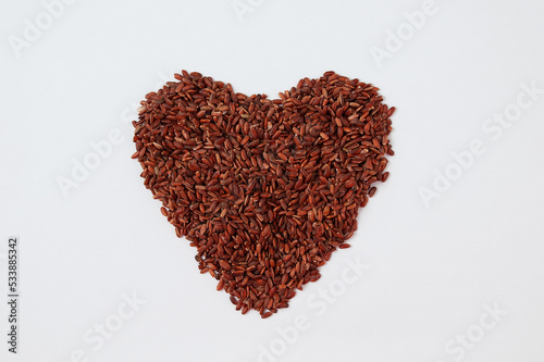 Red kernel rice on a white background in the shape of a heart.
