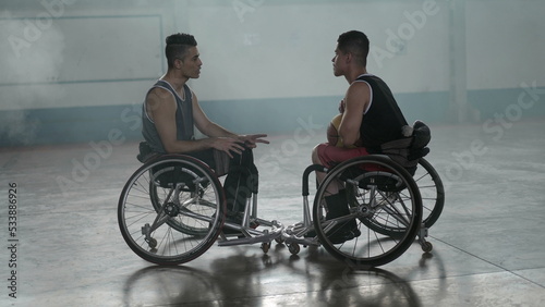 Two disabled athletes in conversation in wheelchairs. Handicapped basketball players wearing sportwear