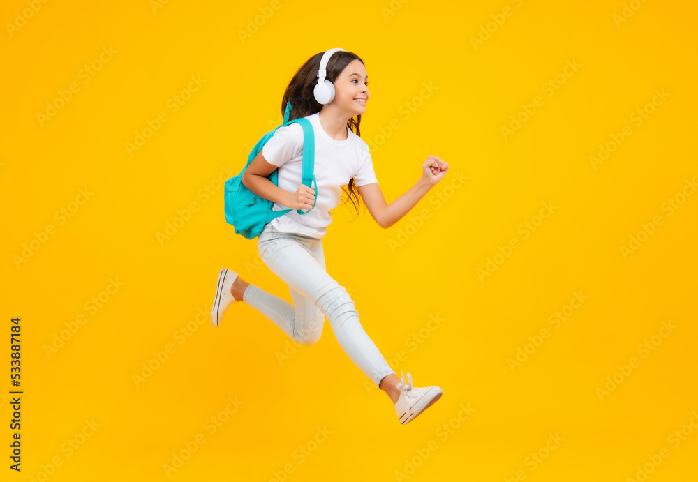 Schoolgirl with backpack hold aplle ready to learn. School children with school bag on isolated yellow studio background. Excited teenager, jump and run, jumping child.