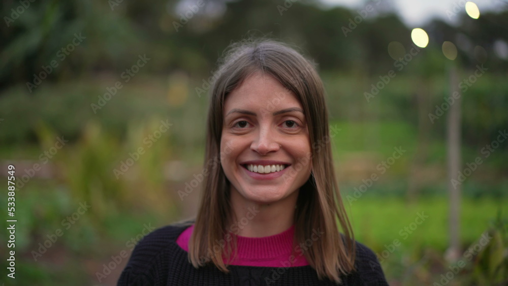 Portrait of a woman in 30s closeup face smiling at camera. Happy person in rural background Portrait of a woman in 30s closeup face smiling at camera. Happy person in rural background