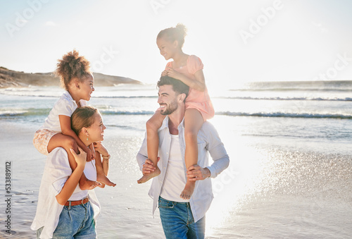 Nature, smile and happy family at the beach to relax in freedom, peace and memories together in summer. Travel, mother and father in an interracial relationship carrying children on holiday at sea photo