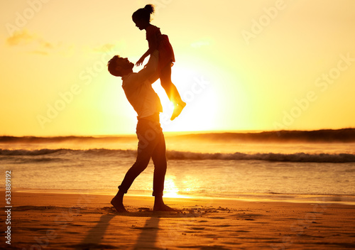 Father, girl and beach at sunset happy, silhouette of man and child together play on sand. Parent, ocean and sun, rising or setting over the horizon in nature, on vacation or family travel by the sea