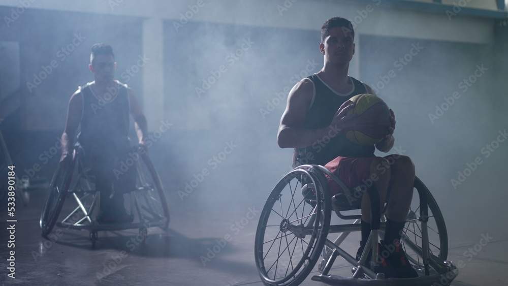 Disabled basketball athletes in wheelchairs with dramatic lighting indoors