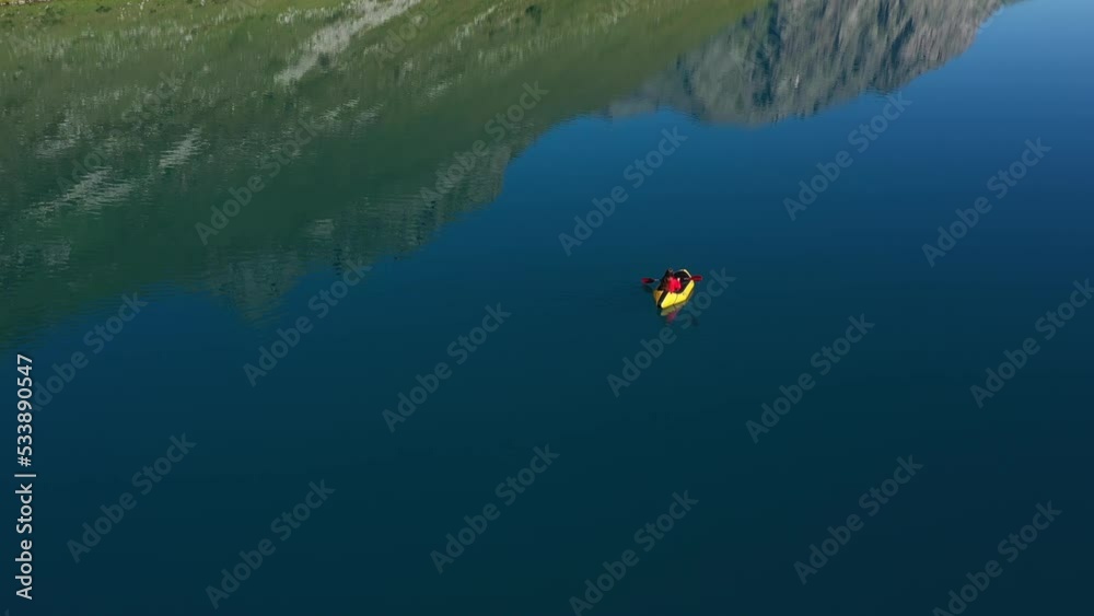 Woman Paddling on Packraft on Beautiful Mountain Lake. Aerial View Woman Paddling on Packraft on Beautiful Mountain Lake. Aerial View