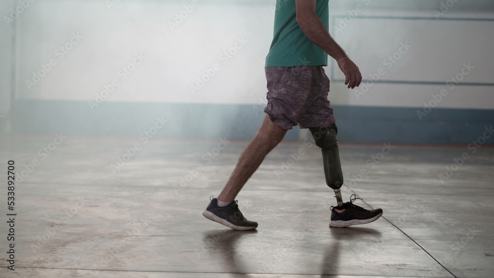 A disabled middle aged man walking with his prosthetic leg indoors A disabled middle aged man walking with his prosthetic leg indoors