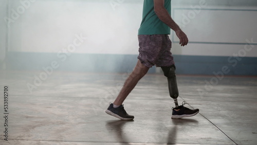 A disabled middle aged man walking with his prosthetic leg indoors © Marco