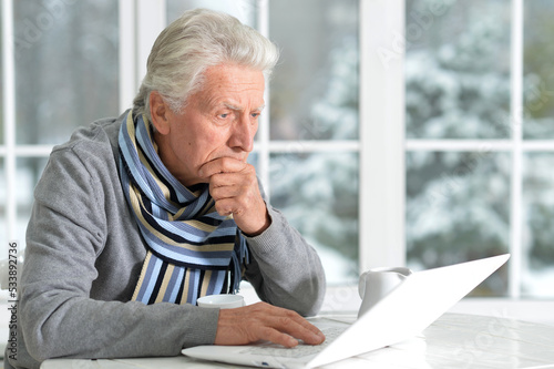 Elderly man sits on the background of the window in winter