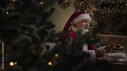 Busy Santa Claus is getting ready to Christmas season, working in his residence, dealing with correspondence, reading letters from children with great pleasure, Slow motion.