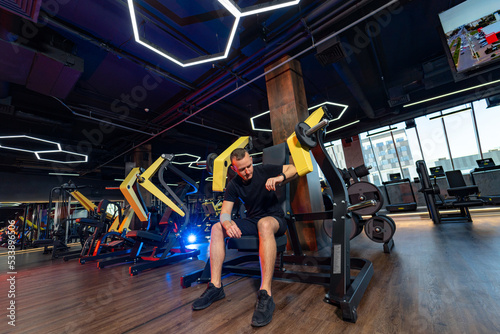 Sporty strong guy with motivation doing exercises. Young handsome man training in modern gym.