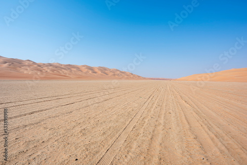 Track in the desert going thru a sabkha with blue sky and copy space. Middle East, Arabian Peninsula 