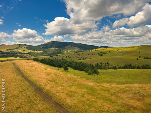 Beautiful white clouds are flowing across the sky over the green Zlatibor hills landscape on sunny summer day © Bits and Splits