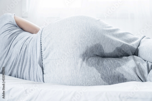 closeup woman with wet pants because of Stress urinary incontinence can't control her pee while sleeping in bed