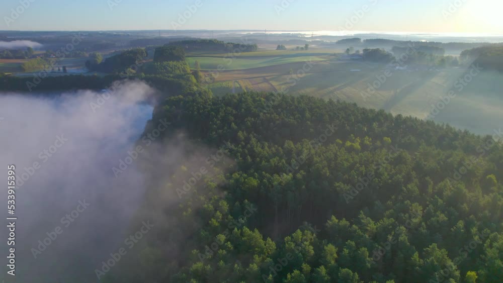 Aerial View of Farmland Foggy Morning in Poland. Amazing Nature Landscape Wonderful Morning Sunrise. Sun Rays Break Through Foliage and Fog of Trees. Early Morning Fog Rising up Above Shiny Hills. Aerial View of Farmland Foggy Morning in Poland. Amazing Nature Landscape Wonderful Morning Sunrise. Sun Rays Break Through Foliage and Fog of Trees. Early Morning Fog Rising up Above Shiny Hills.