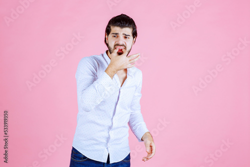 Photos Man in a white shirt whisting with fingers
