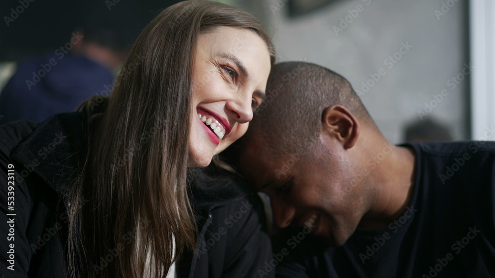 Romantic diverse couple laughing and smiling. A black man leaning on white girl shoulder showing love and affection Romantic diverse couple laughing and smiling. A black man leaning on white girl shoulder showing love and affection