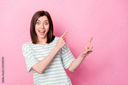 Photo of staring open mouth girl with bob hairstyle dressed striped t-shirt indicating empty space isolated on pink color background © deagreez