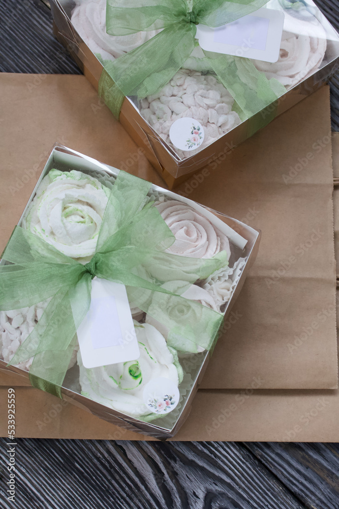 Homemade marshmallows in a gift box. Tied with ribbon. Paper bag from craft paper. Zephyr flowers. On black pine boards. Taken from above. Homemade marshmallows in a gift box. Tied with ribbon. Paper bag from craft paper. Zephyr flowers. On black pine boards. Taken from above.