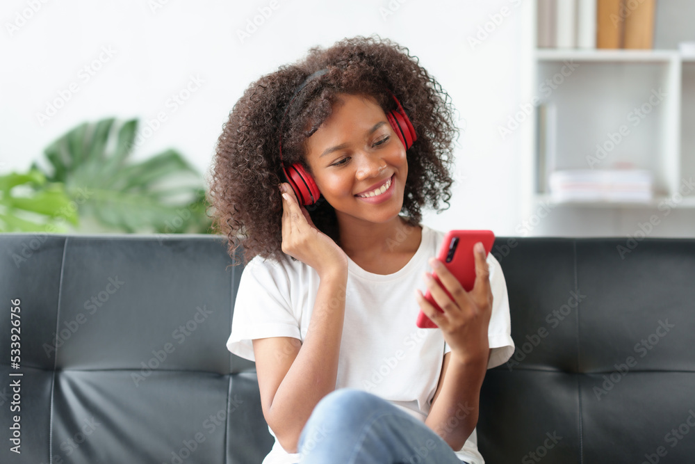 Bright and cute Asian young woman wearing headphones sit on the sofa and using smartphone to listen to music happy and relax listening to music at home. Bright and cute Asian young woman wearing headphones sit on the sofa and using smartphone to listen to music happy and relax listening to music at home.