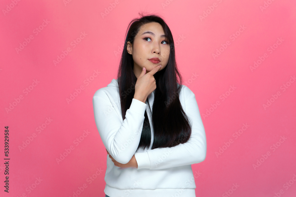 Pensive puzzled young asian girl looking up, considering problem solution, pondering decision on pink studio background Pensive puzzled young asian girl looking up, considering problem solution, pondering decision on pink studio background