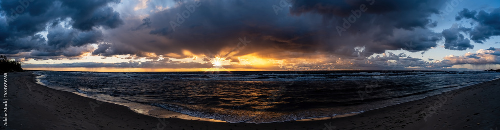 Dramatic sunset nature background. Sunset sea coast. Panoramic seascape with golden sunbeams reflected in the ocean water.