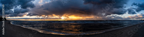 Dramatic sunset nature background. Sunset sea coast. Panoramic seascape with golden sunbeams reflected in the ocean water.