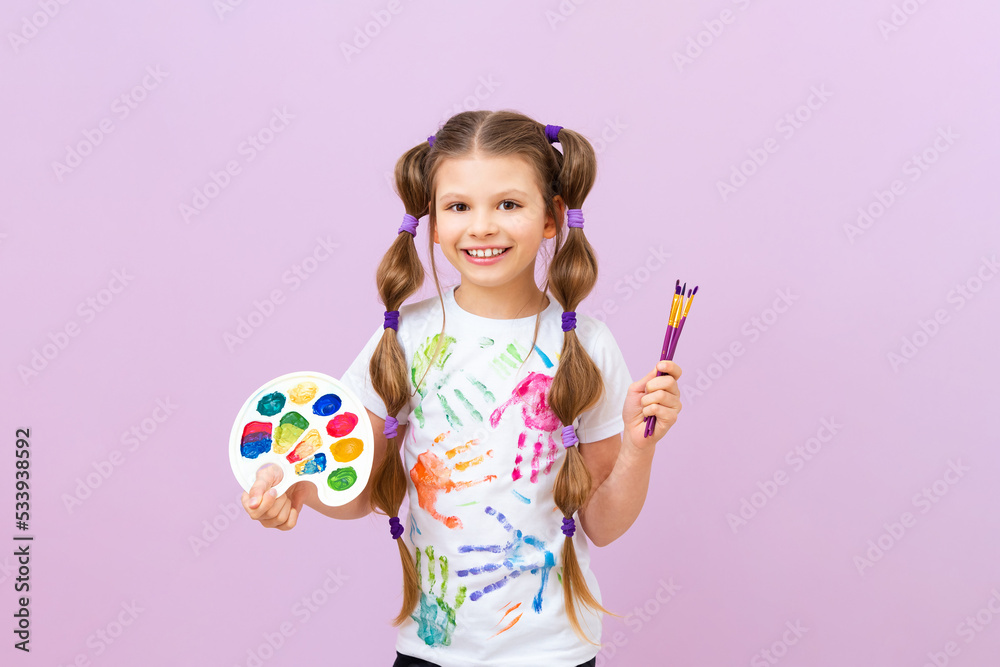 A beautiful little girl with paints and a palette in her hands, the concept of painting pictures, children's creativity and drawing.