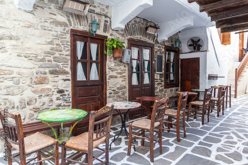 Fototapeta Naklejka Na Ścianę i Meble -  Naxos island, Cyclades Greece. Traditional outdoors cafe wooden ornate chair table on paved street.