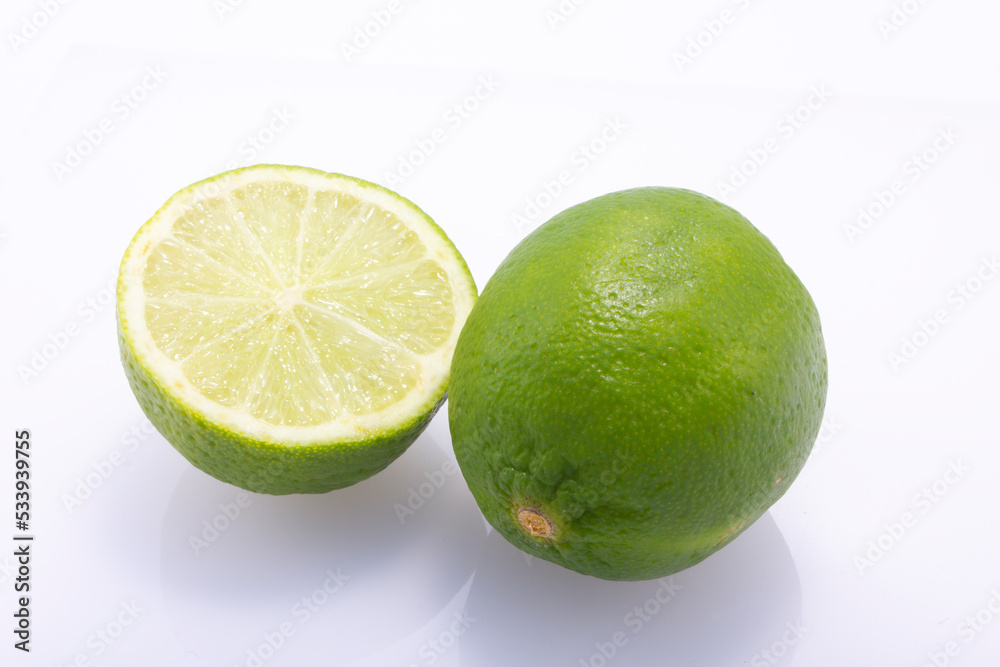 Green limes, cut in half and whole, isolated against a white background. Green limes, cut in half and whole, isolated against a white background.