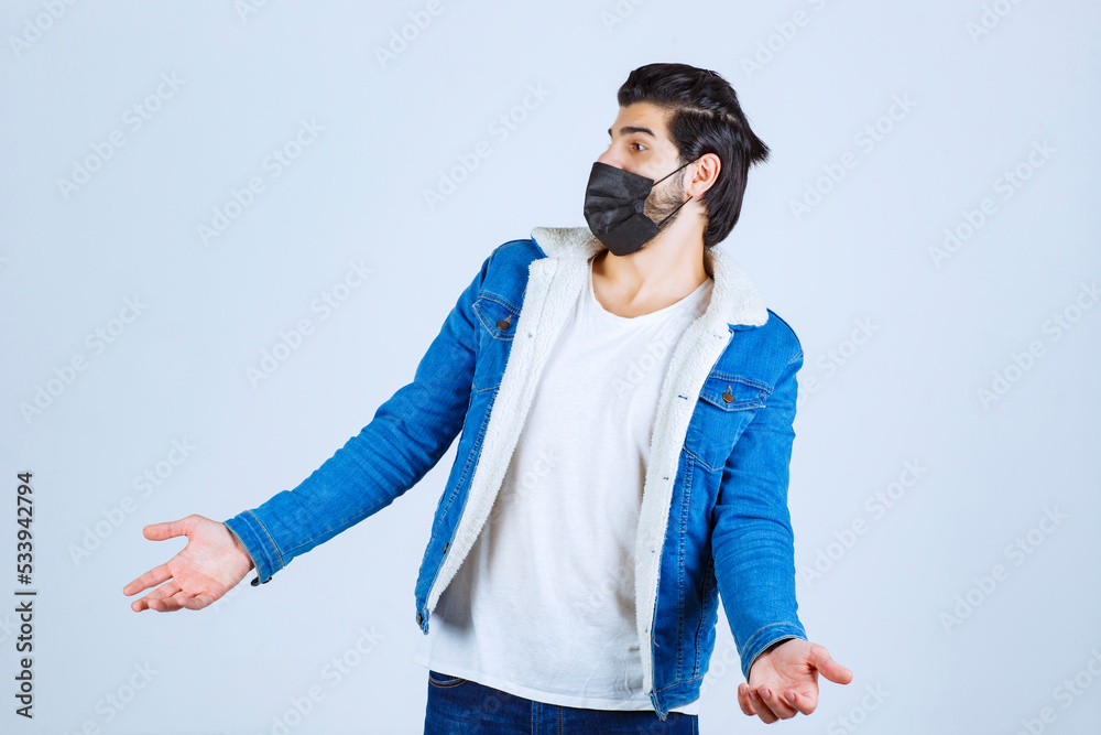 Fototapeta premium Man in black mask looks confused and trying to explain himself