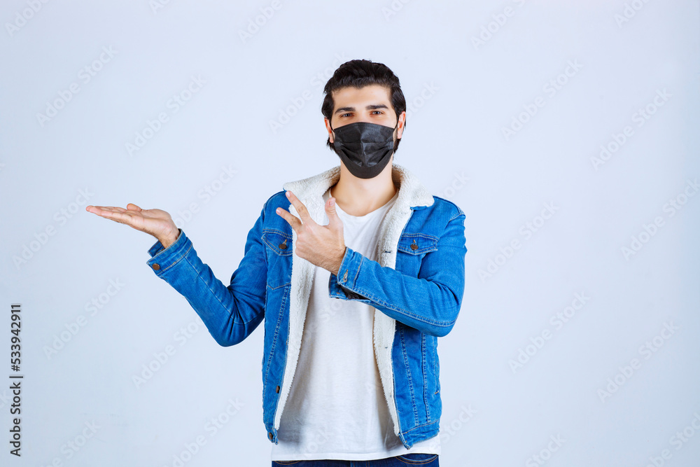 Man wearing black mask and pointing to the left Man wearing black mask and pointing to the left