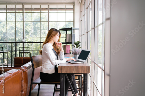Professional confident Asian businesswoman working on laptop computer in the office area. Woman role in online business leadership and entrepreneurship. Image with copy space. © artitwpd